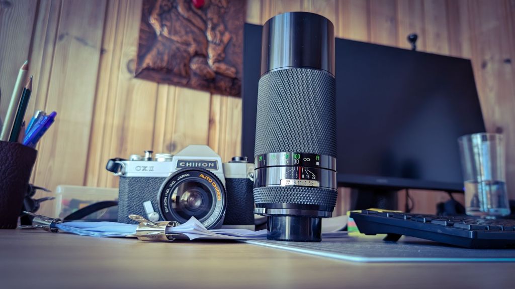A picture of the Chinon with an extra lens, standing on my happy messy desk.